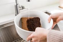 Load image into Gallery viewer, Compressed coconut coir block being hydrated with water in a bowl
